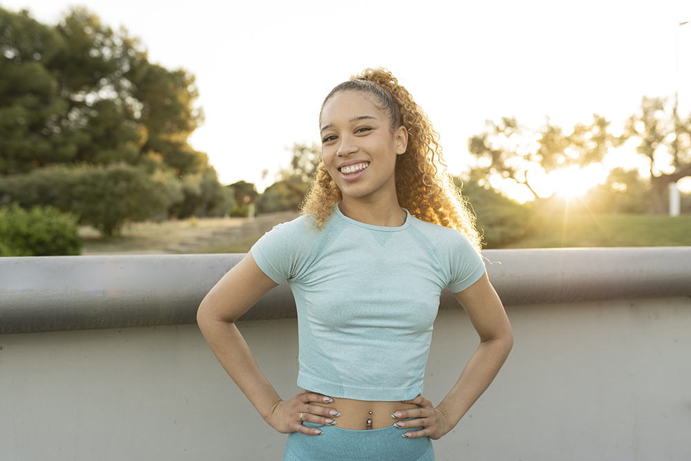 Woman smiling outdoors at sunrise after her daily collagen drink